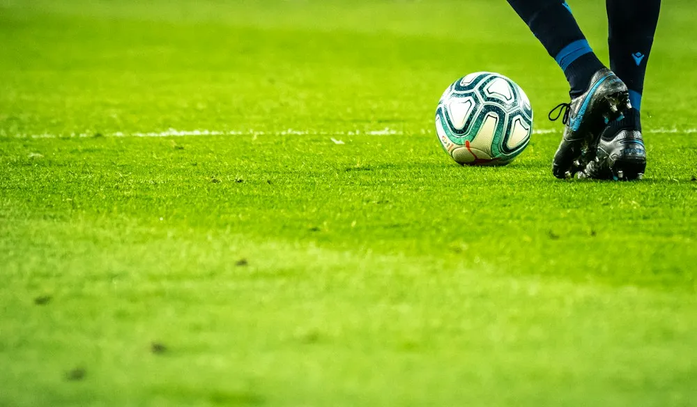 Balón y jugador de fútbol sobre césped
